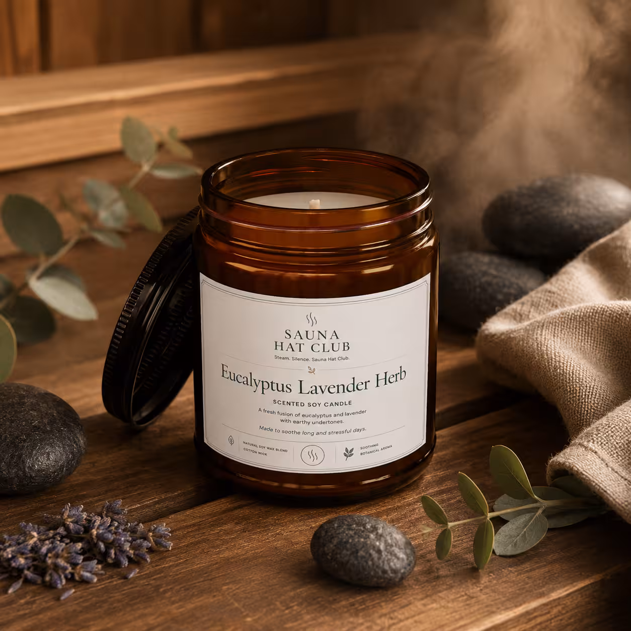 Front view 9oz clear jar Eucalyptus Lavender Herb soy candle with black lid and sauna props
